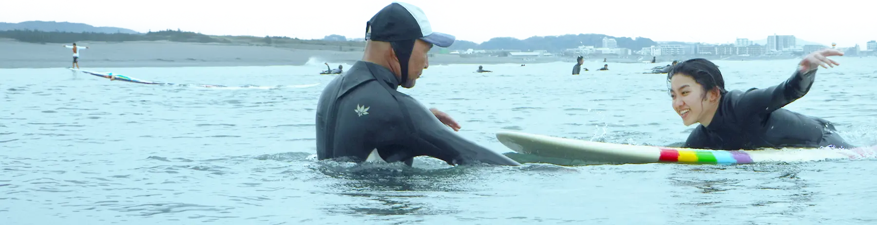 海でサーフィンのレッスンを受けるスクール参加者
